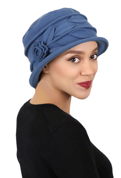 woman in blue grey fleece hat with rose and leaves, same color as the hat. 